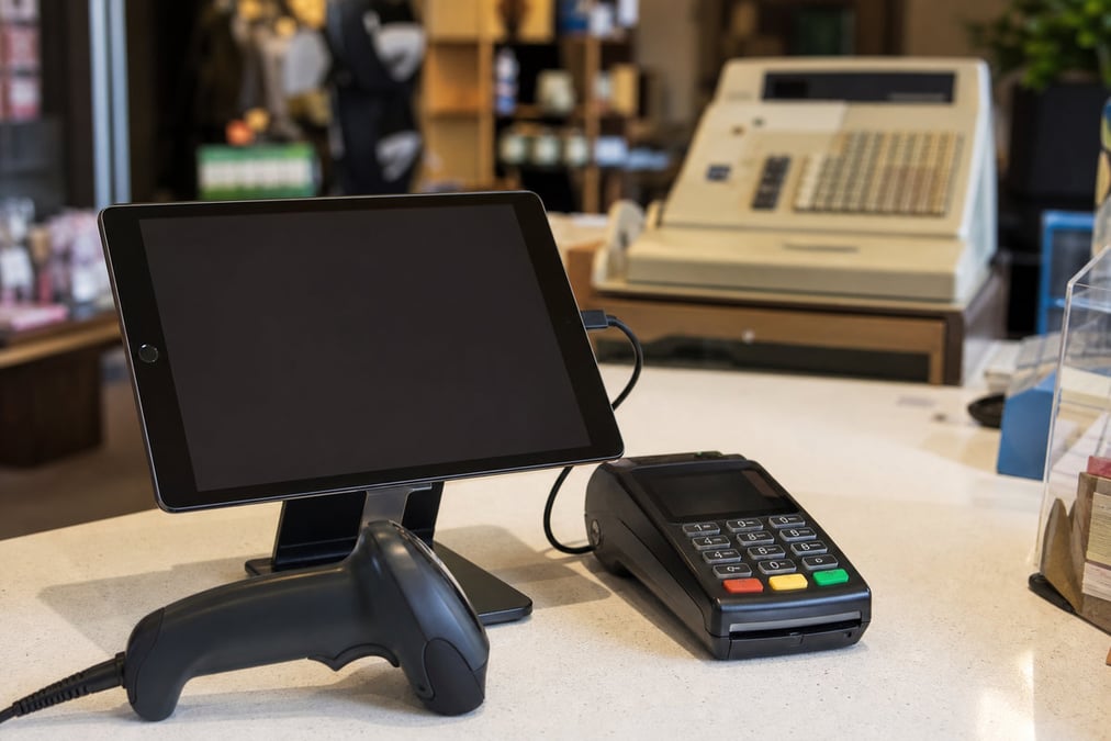 A smiling customer makes a contactless payment at a bustling café counter.