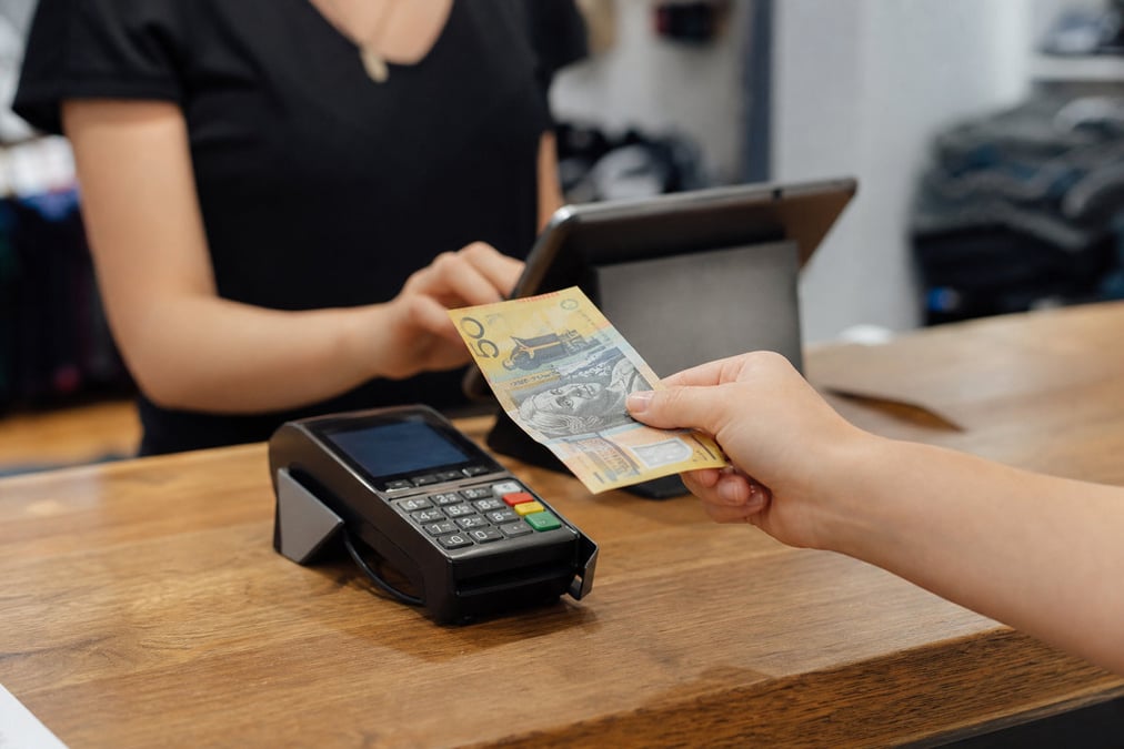 A restaurant staff member uses a POS system to process a credit card payment at the counter.