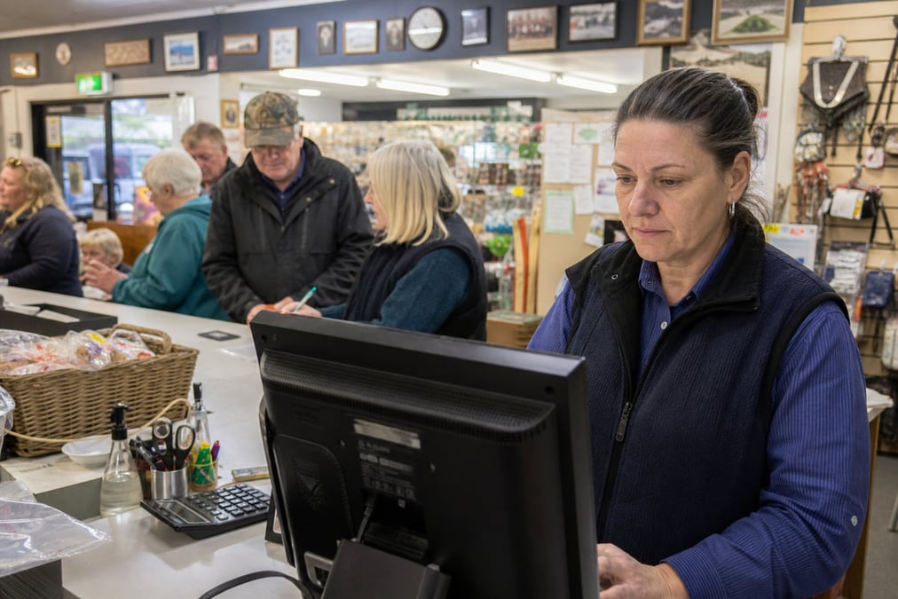 Two people packing online orders in a small business setting with a laptop.