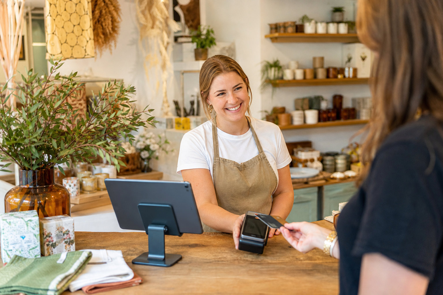 Barista wearing an apron processes a payment in a cozy Portuguese café.
