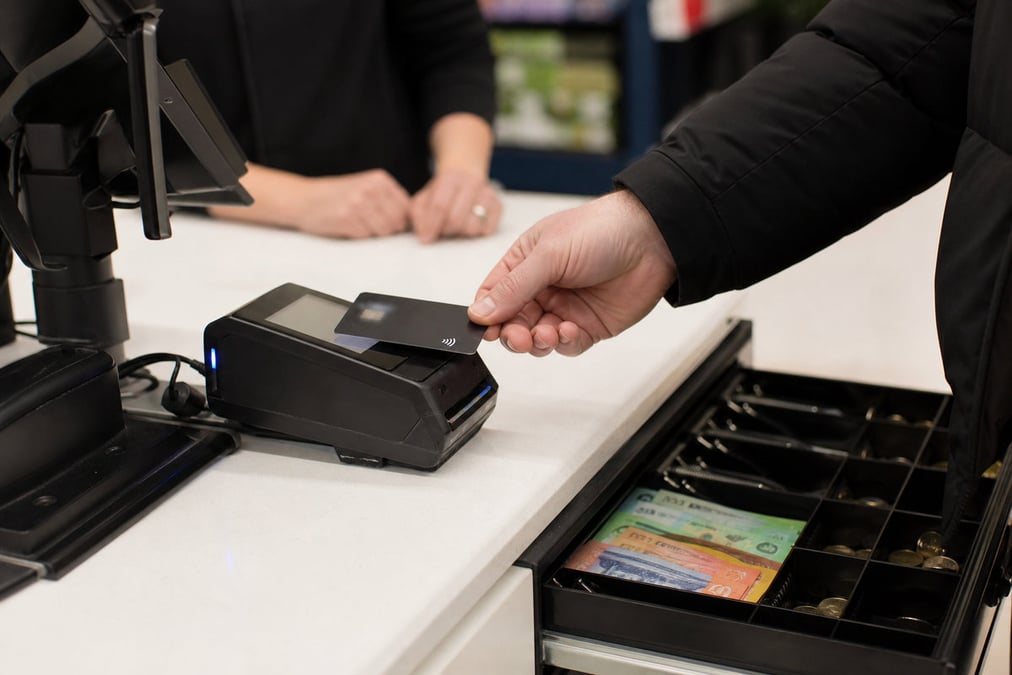 Close-up of hands completing a payment transaction at a retail checkout using a bank card.