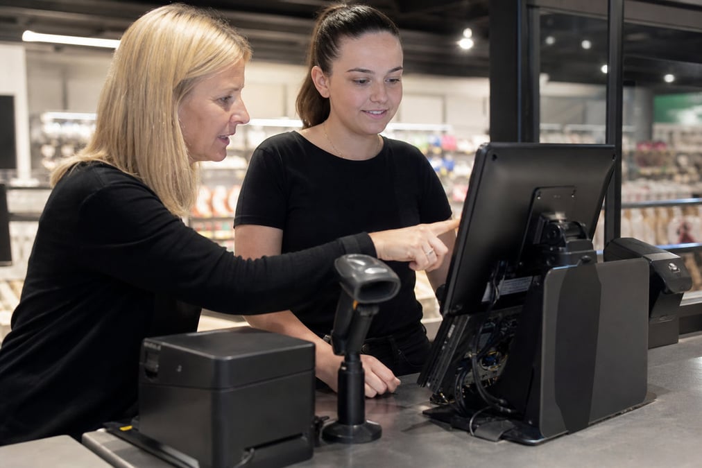 Smiling female cashier using a touchscreen in a modern restaurant setting.