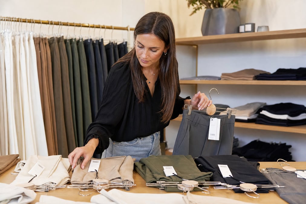Delighted woman shopping in a stylish boutique, holding colorful bags.