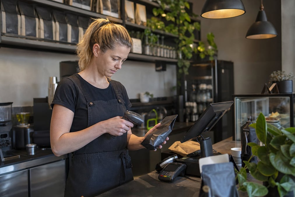 A cafe worker navigating a modern touchscreen system to manage orders efficiently.