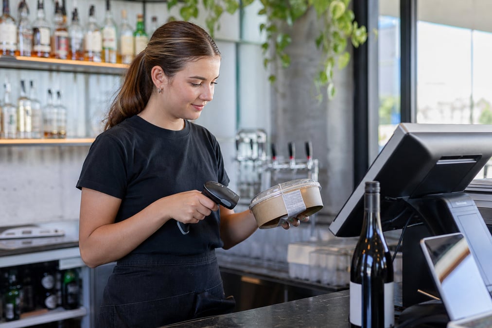 A diner uses a handheld POS system for digital tipping in a casual restaurant setting.