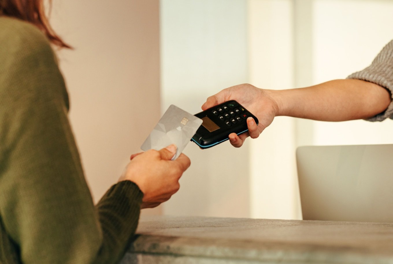 Customer tapping a card on a payment terminal held by a staff member