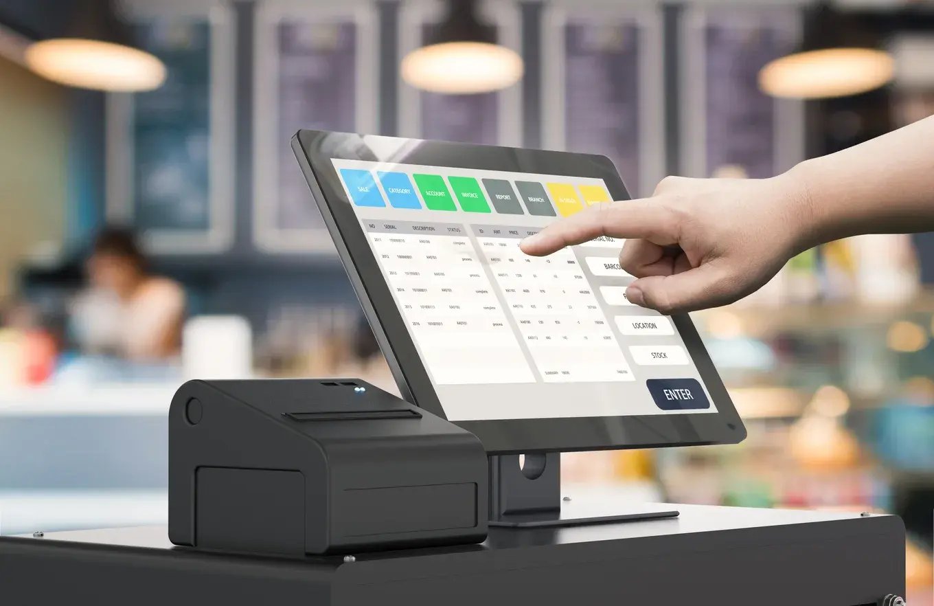 Hand tapping a touchscreen POS terminal next to a receipt printer in a cafe