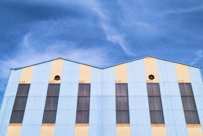 Blue and cream striped warehouse roofline against a blue sky