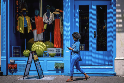 Woman walking past a bright blue fashion shopfront