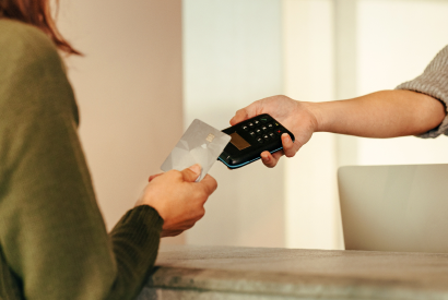 Customer tapping a card on a payment terminal held by a staff member
